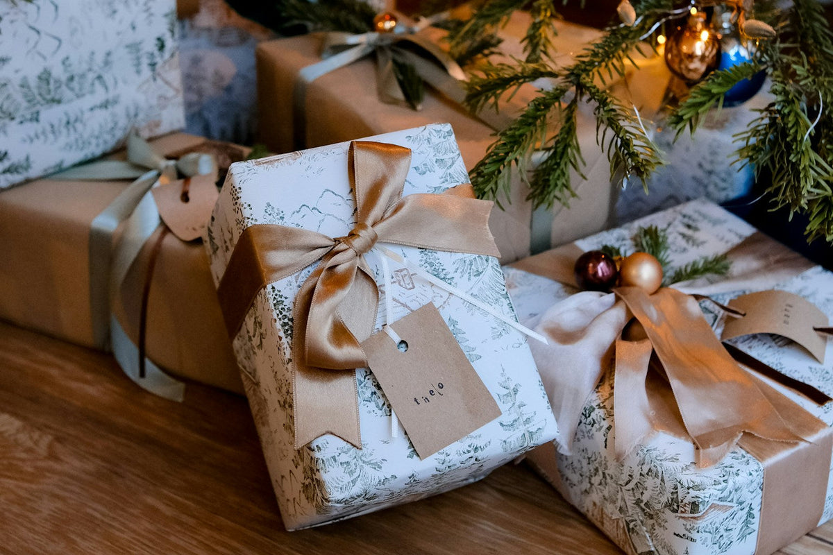 Wrapped Christmas gifts beneath a decorated tree with warm festive lights