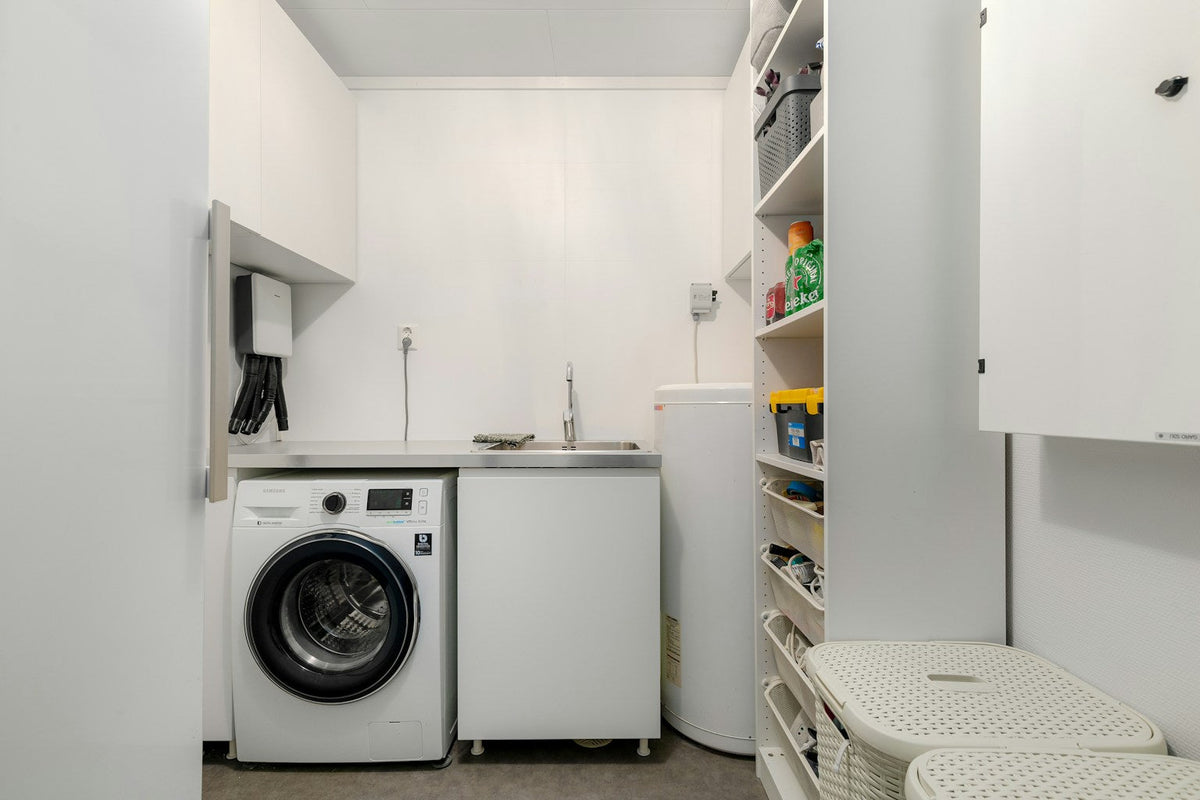Compact white laundry room with front-loading washing machine, countertop and open storage shelves